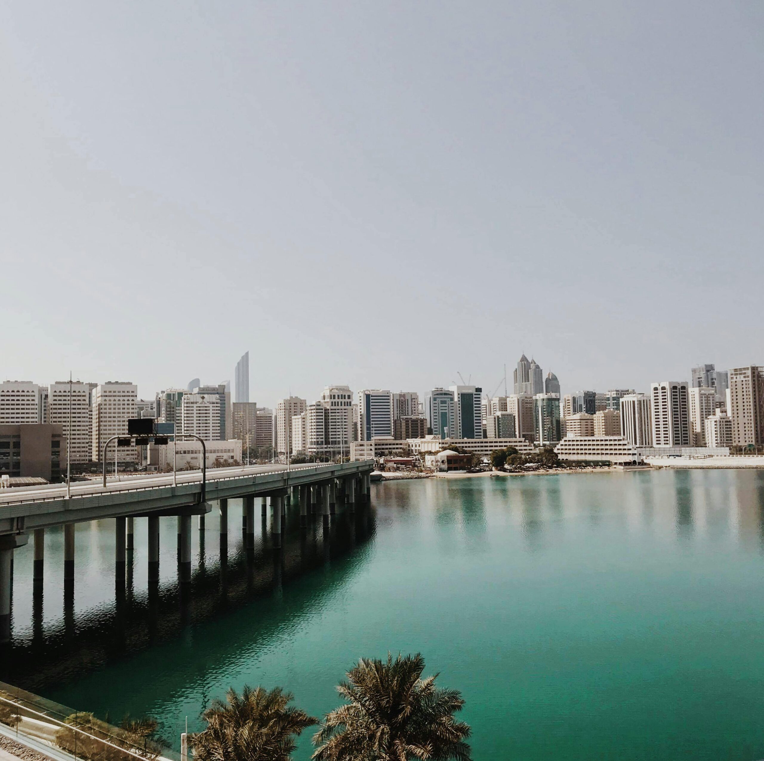 Explore the dynamic cityscape of Abu Dhabi featuring a modern bridge and skyline over tranquil waters.
