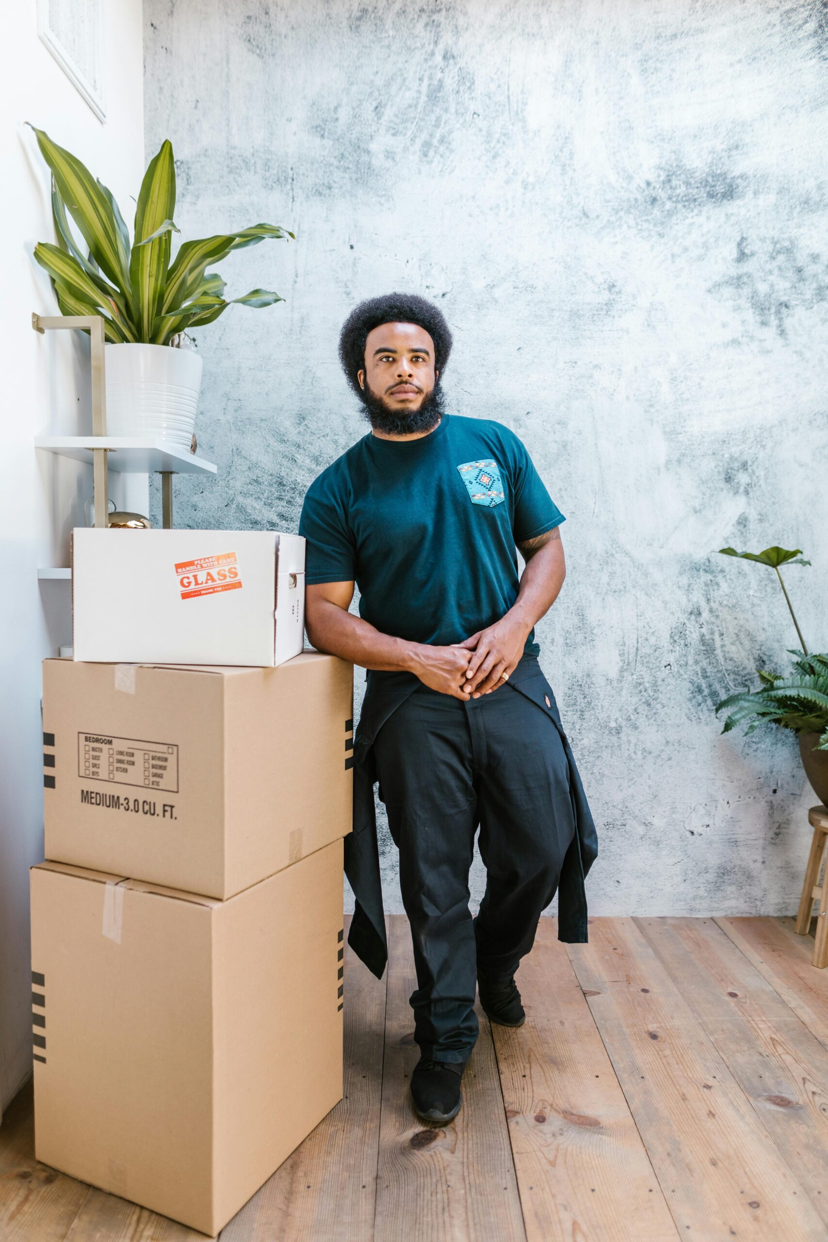 African American man preparing for relocation with cardboard boxes and plants in a modern interior.