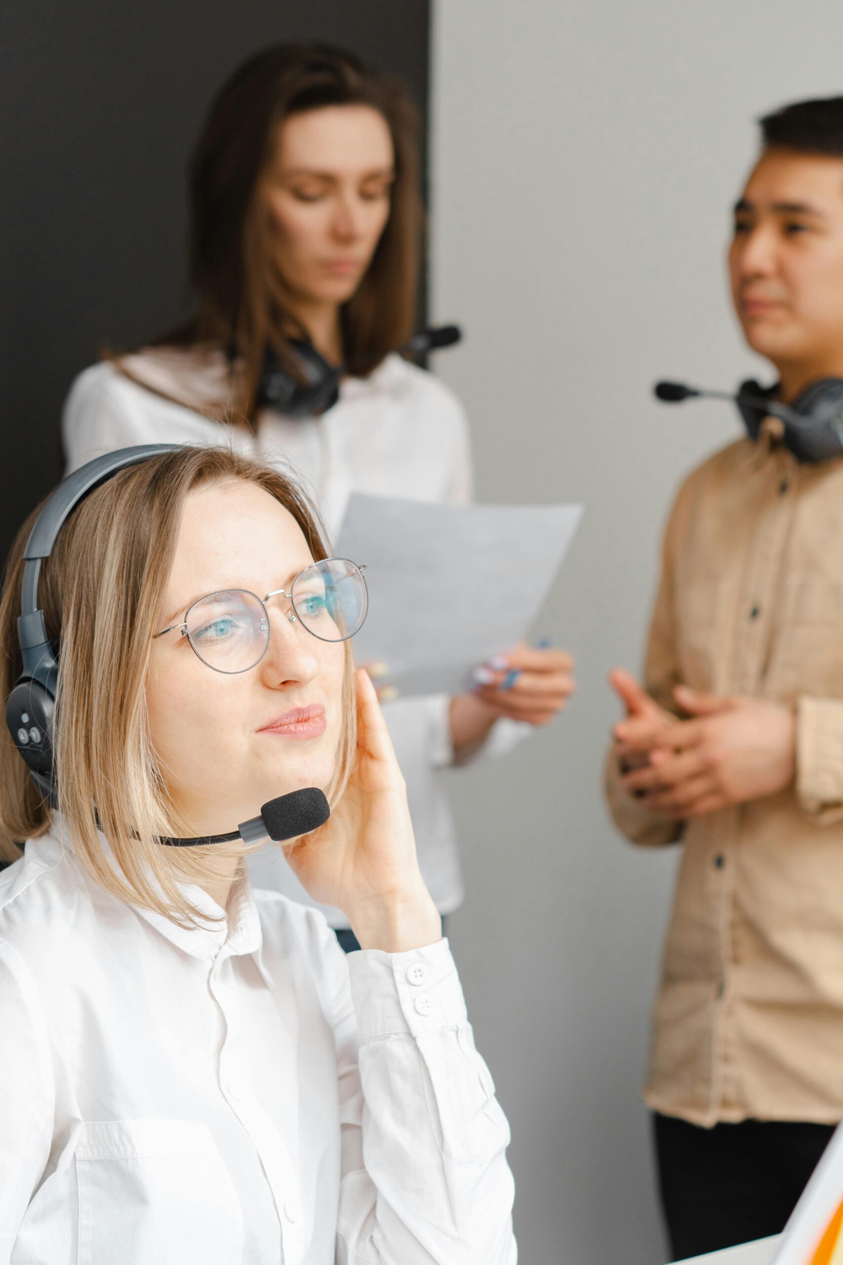 Team of professionals in a call center discussing customer service strategies while wearing headsets.